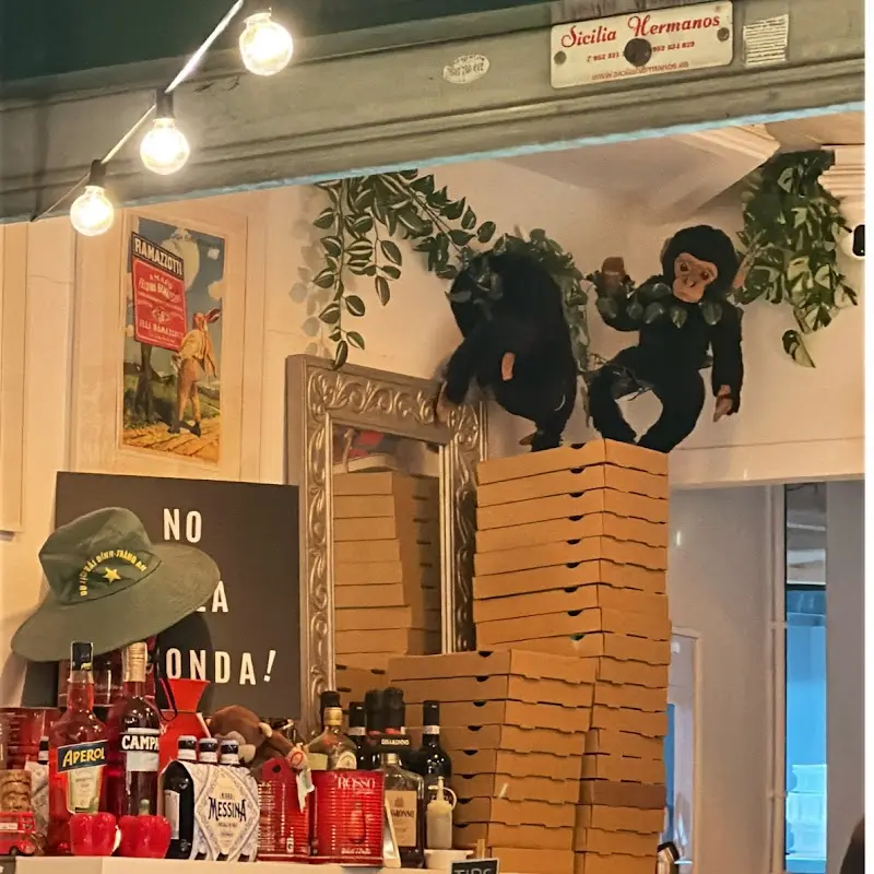 Cajas de pizza apiladas, monos de peluche y botellas de aperitivo en la decoración del local