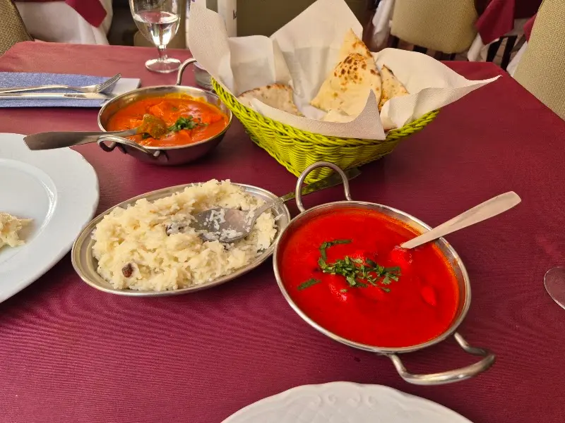 Pollo en salsa tikka masala, arroz basmati y pan naan sobre mantel granate