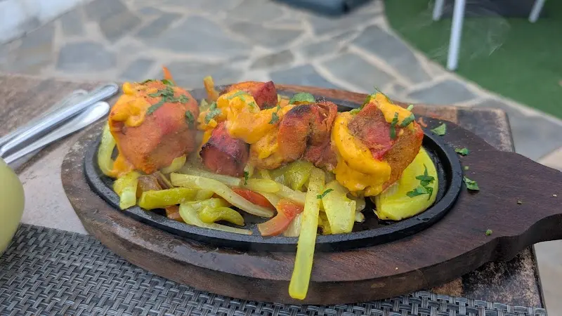 Brochetas de pollo con salsa de queso sobre verduras en plancha caliente