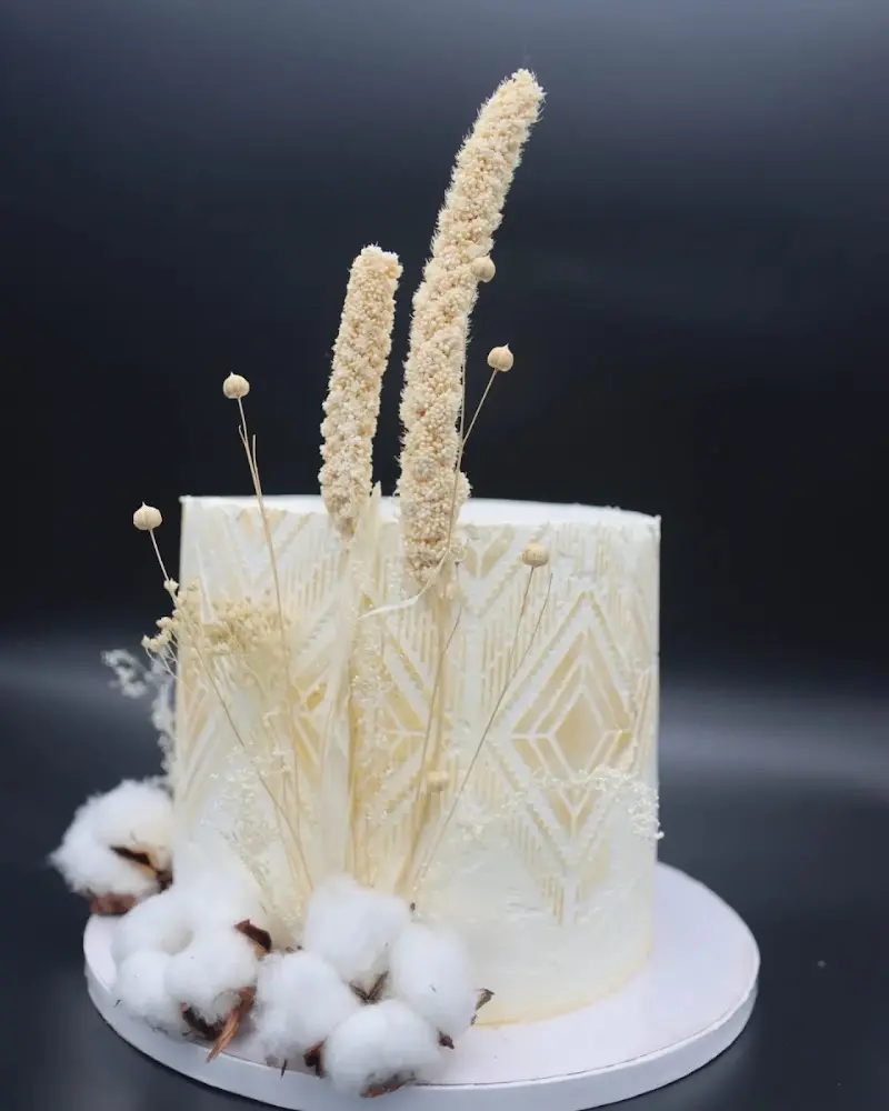 Tarta blanca decorada con espigas secas, flores de algodón y relieve geométrico