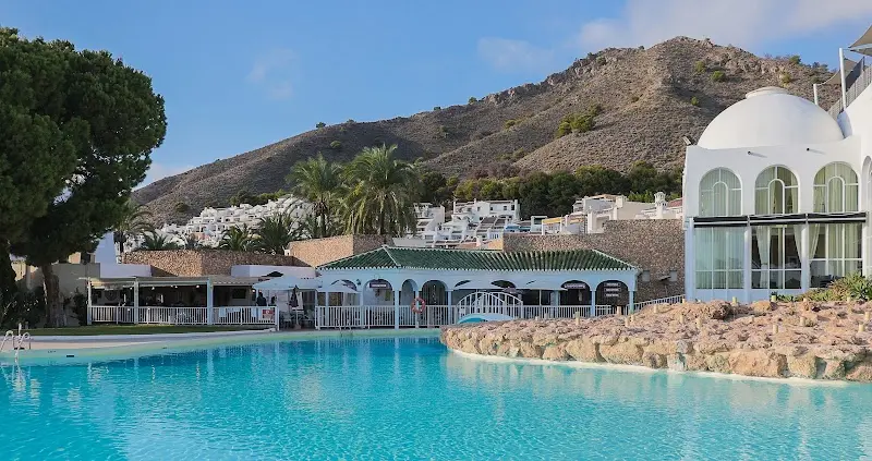 Gran piscina de la urbanización con edificios blancos y la montaña al fondo