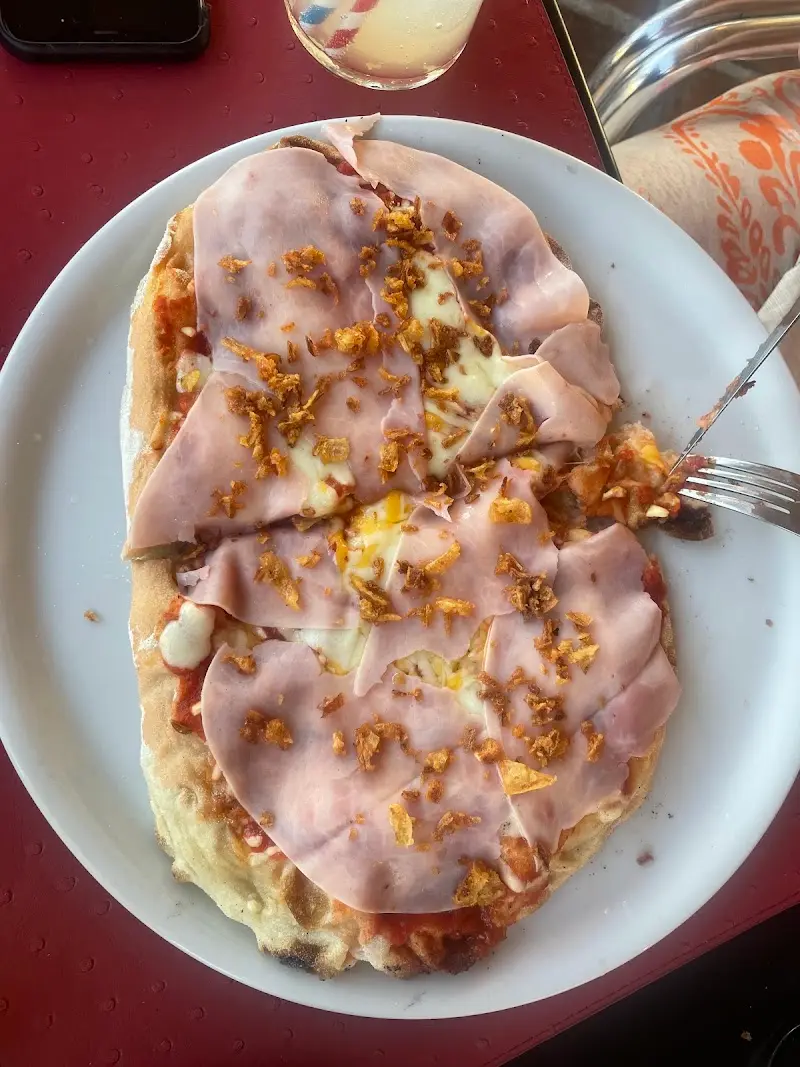 Pizza alargada con jamón cocido, queso fundido y cebolla frita crujiente
