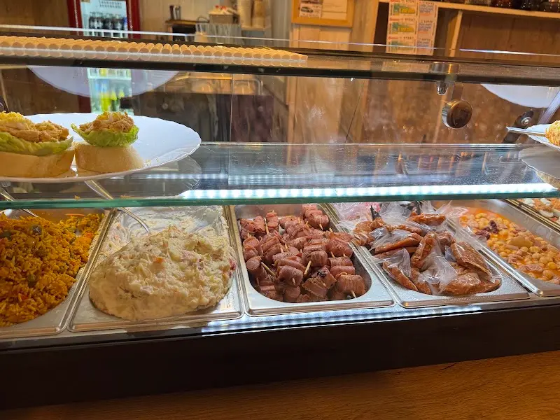 Bandejas de tapas en la barra: arroz, ensaladilla, pinchos con beicon y salchichas