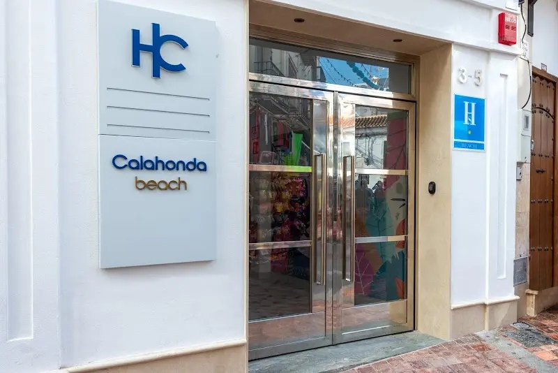 Entrada del HC Calahonda Beach con puerta de cristal, rótulo del hotel y placa azul