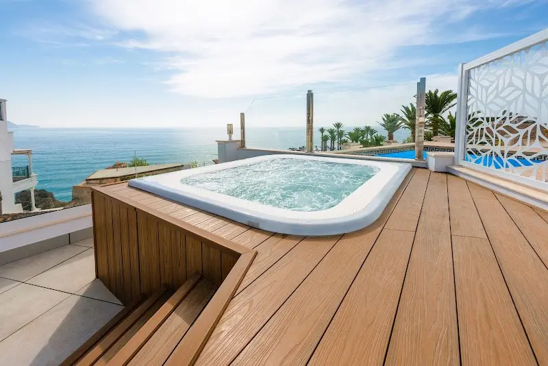 Jacuzzi en la azotea con tarima de madera, palmeras y el Mediterráneo al fondo
