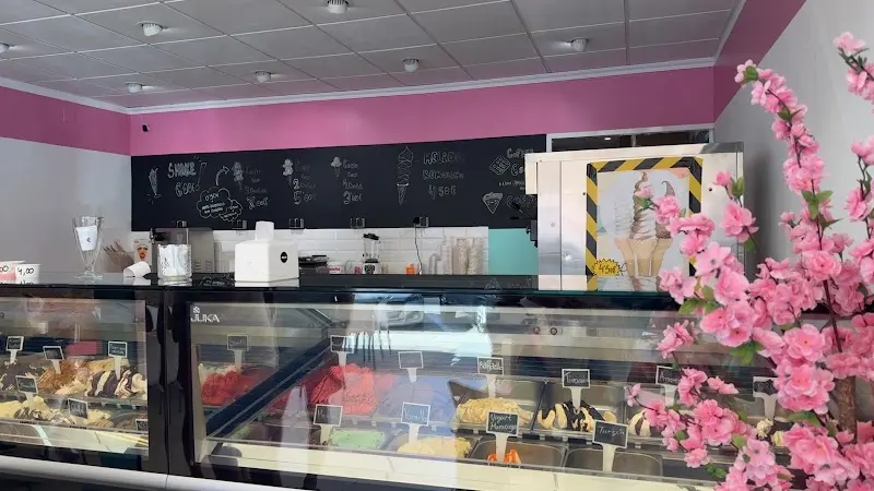 Interior con vitrina de helados, pizarra con la carta y ramas de flores rosas
