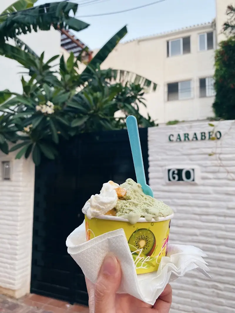 Tarrina de helado con nata y fruta frente a un portal de la calle Carabeo