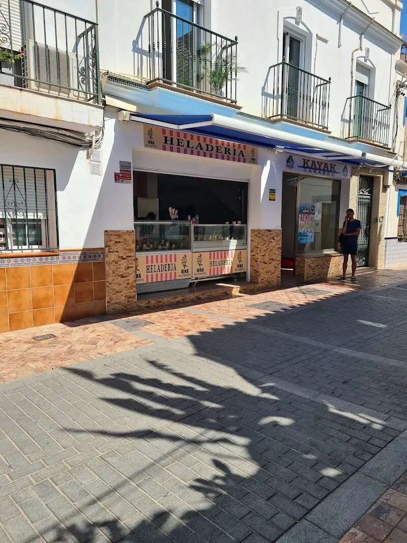 Fachada de la Heladería Kika con mostrador a la calle y toldo azul en una calle peatonal