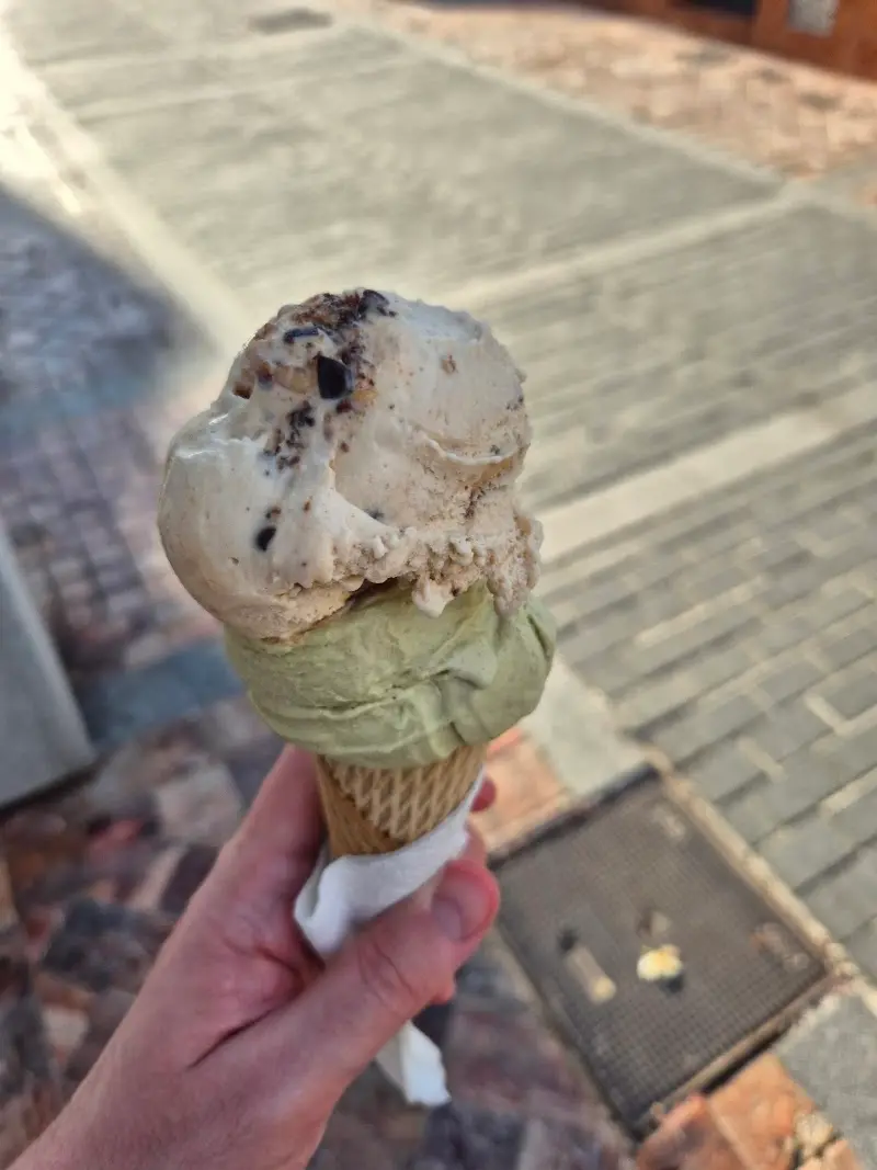 Cucurucho con dos bolas de helado, una de pistacho, sobre el suelo empedrado