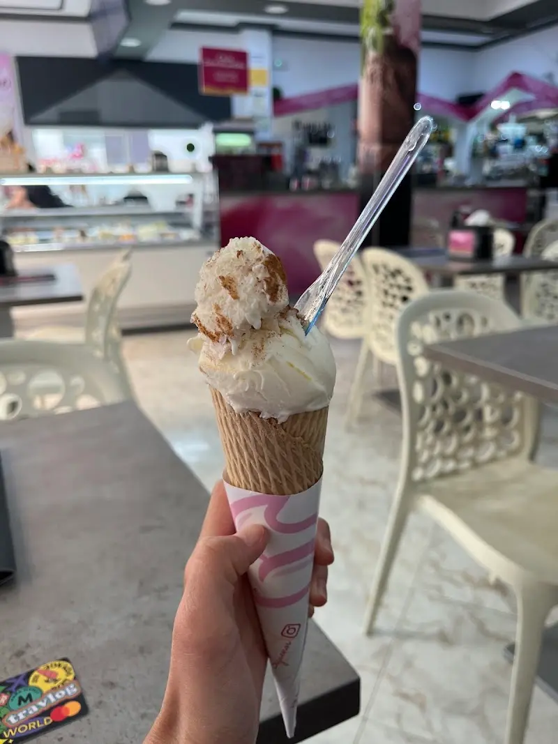 Cucurucho de helado de vainilla con trozos de galleta dentro de la heladería