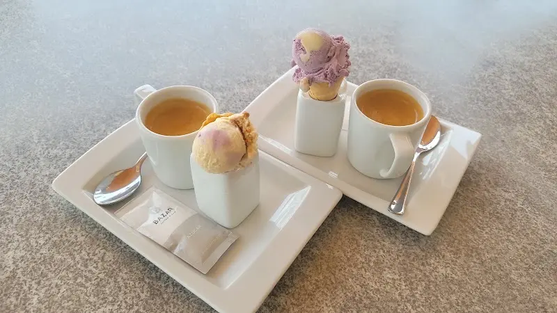 Dos cafés acompañados cada uno de un mini cucurucho de helado sobre bandejas blancas