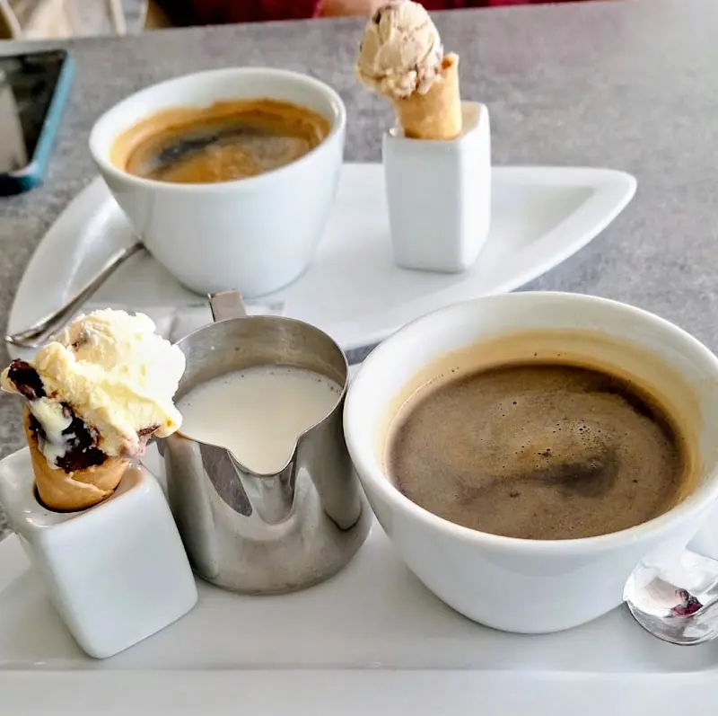 Cafés con jarrita de leche y pequeños cucuruchos de helado servidos en la mesa