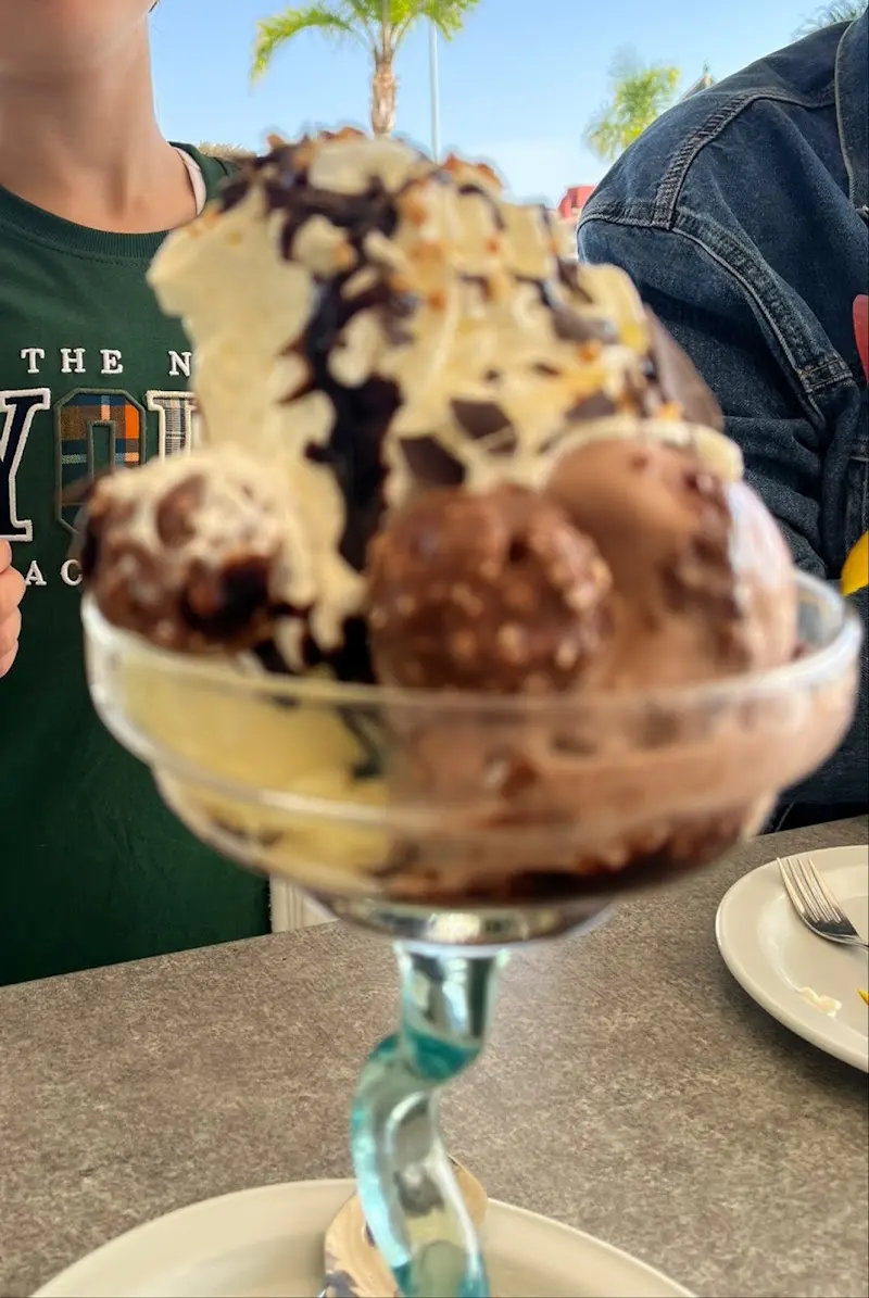 Copa alta de helado de chocolate con bombones, nata y sirope en la terraza de Tropy Sol