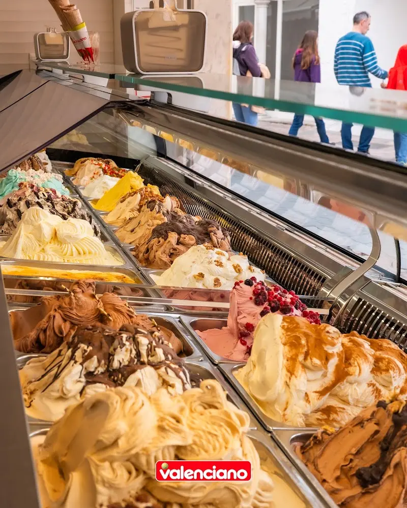 Vitrina con cubetas de helados artesanos de varios sabores, con frutos rojos y chocolate