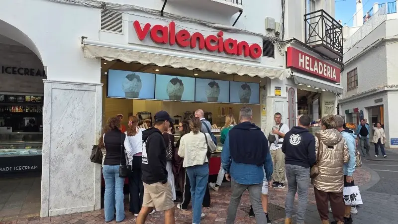 Clientes haciendo cola ante la heladería Valenciano en una calle peatonal de Nerja