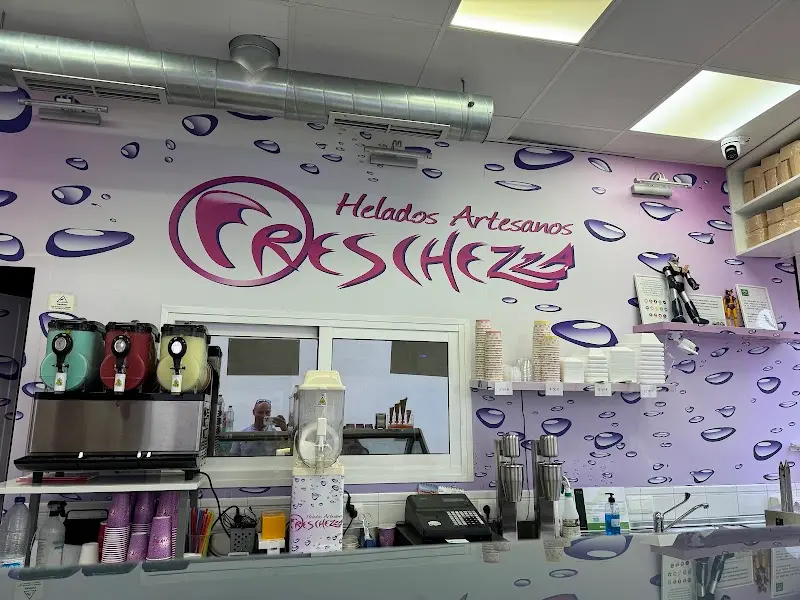 Pared decorada con gotas y el rótulo «Helados Artesanos» sobre la barra de batidos