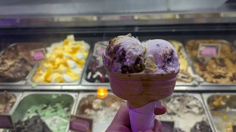 Cucurucho con dos bolas de helado delante de la vitrina de sabores
