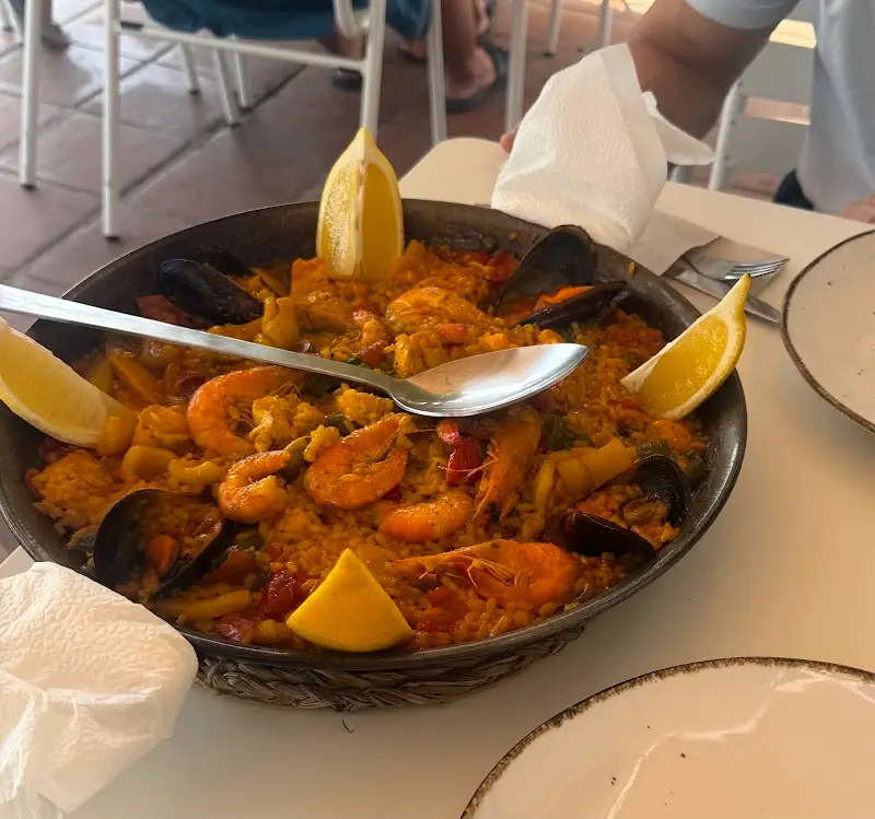 Paella de marisco con gambas, mejillones y limón en paellera sobre la mesa