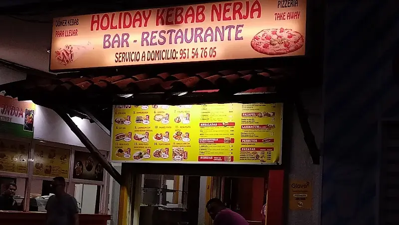 Rótulo luminoso de Holiday Kebab Nerja de noche, con la carta y servicio a domicilio