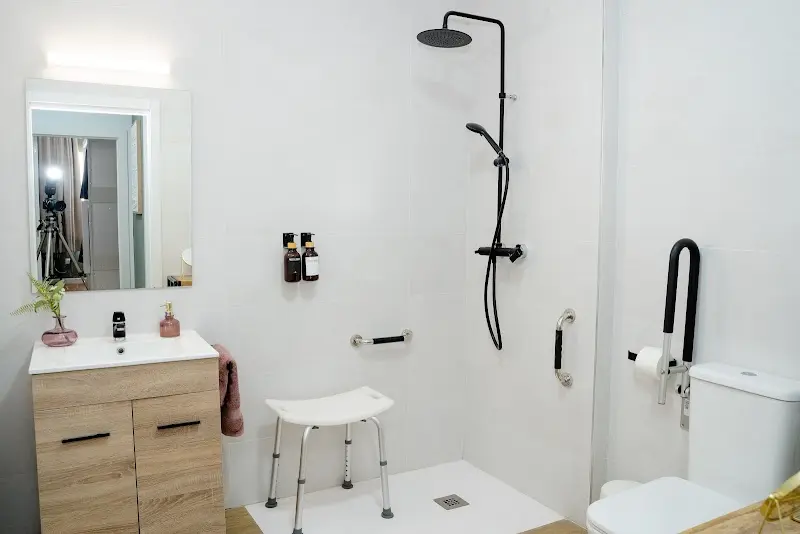 Baño adaptado con ducha a ras de suelo, taburete de ducha y barras de apoyo