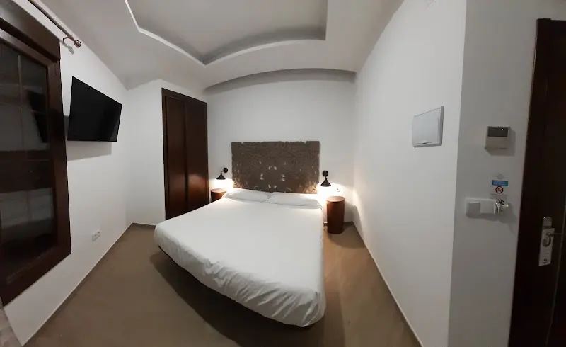 Habitación del Hotel Bajamar con cama de matrimonio, cabecero tallado, televisión y armario