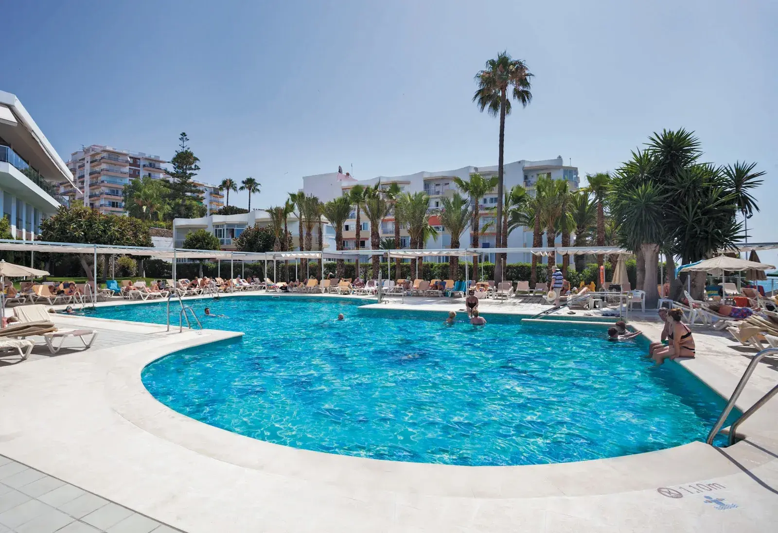 Gran piscina del Hotel Riu Monica rodeada de tumbonas y palmeras