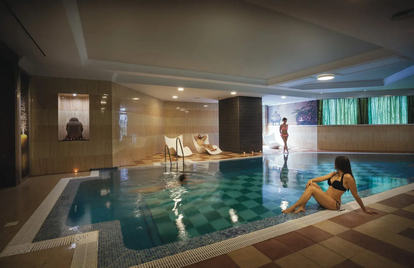 Piscina climatizada interior del spa con tumbonas y luz cálida