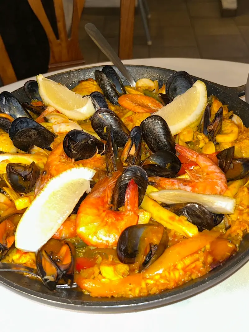 Paella de marisco con mejillones, gambones y rodajas de limón en su paellera