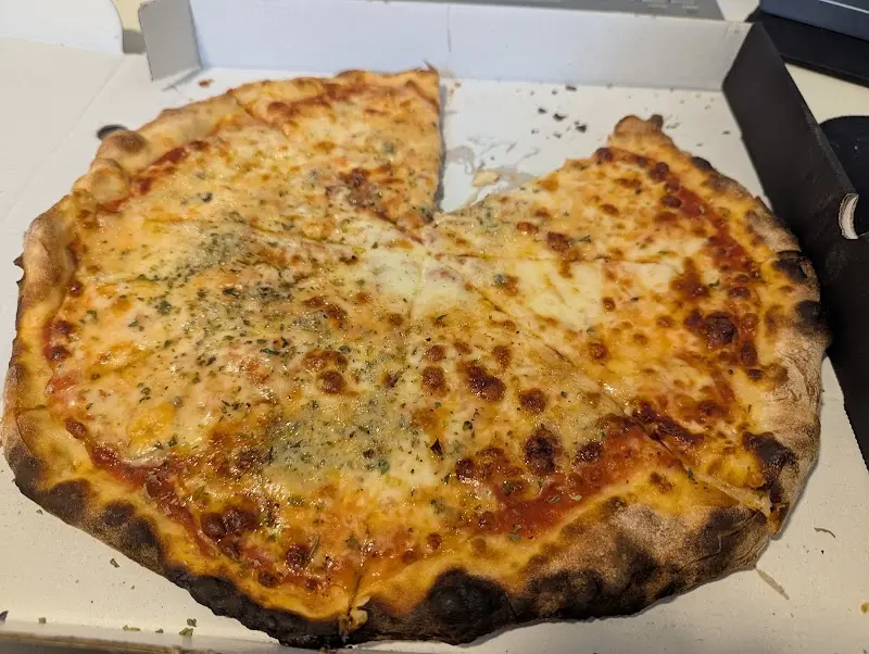 Pizza de queso y tomate cortada en porciones dentro de su caja para llevar