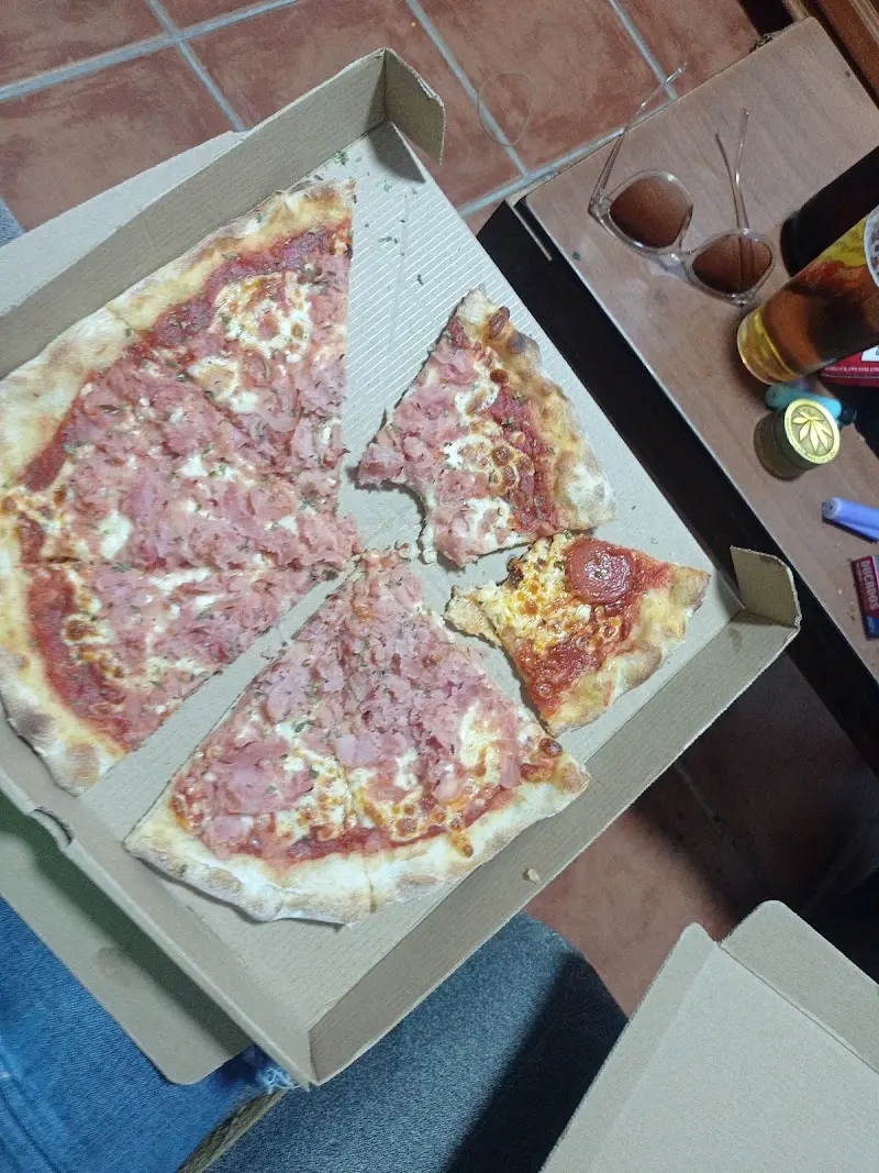 Pizza de jamón york en caja de cartón con una porción de pepperoni aparte