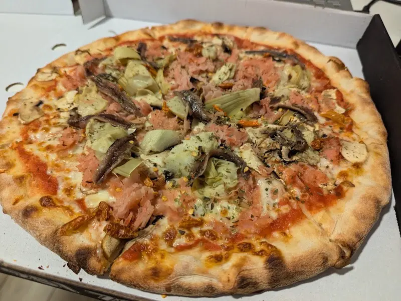 Pizza con alcachofas, anchoas y jamón en caja para llevar