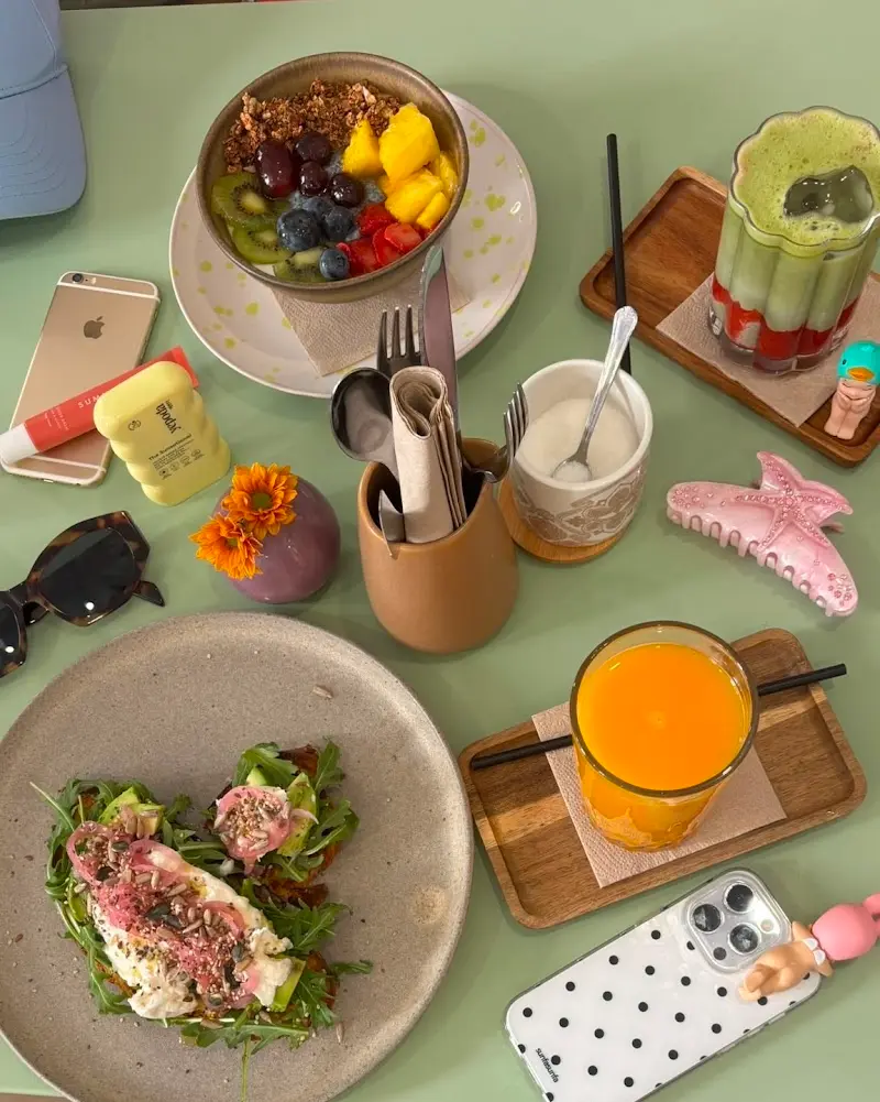 Desayuno visto desde arriba: tostada con huevo y rúcula, bol de fruta con granola y zumo de naranja