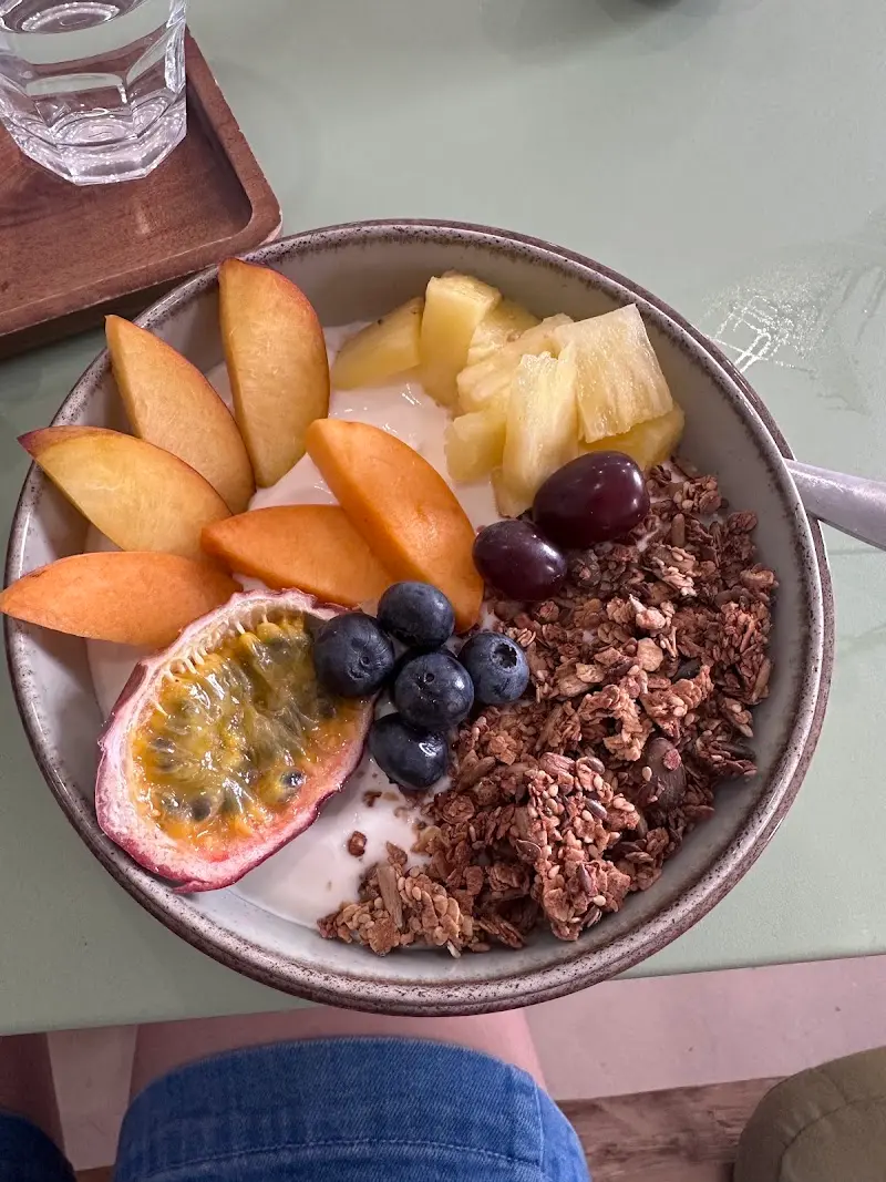 Bol de yogur con granola, melocotón, piña, arándanos, uvas y maracuyá