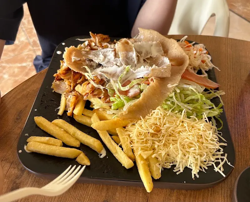 Plato de kebab con pan de pita, ensalada, queso rallado y patatas fritas