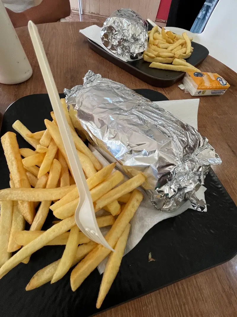 Kebab envuelto en papel de aluminio con patatas fritas en bandeja para llevar