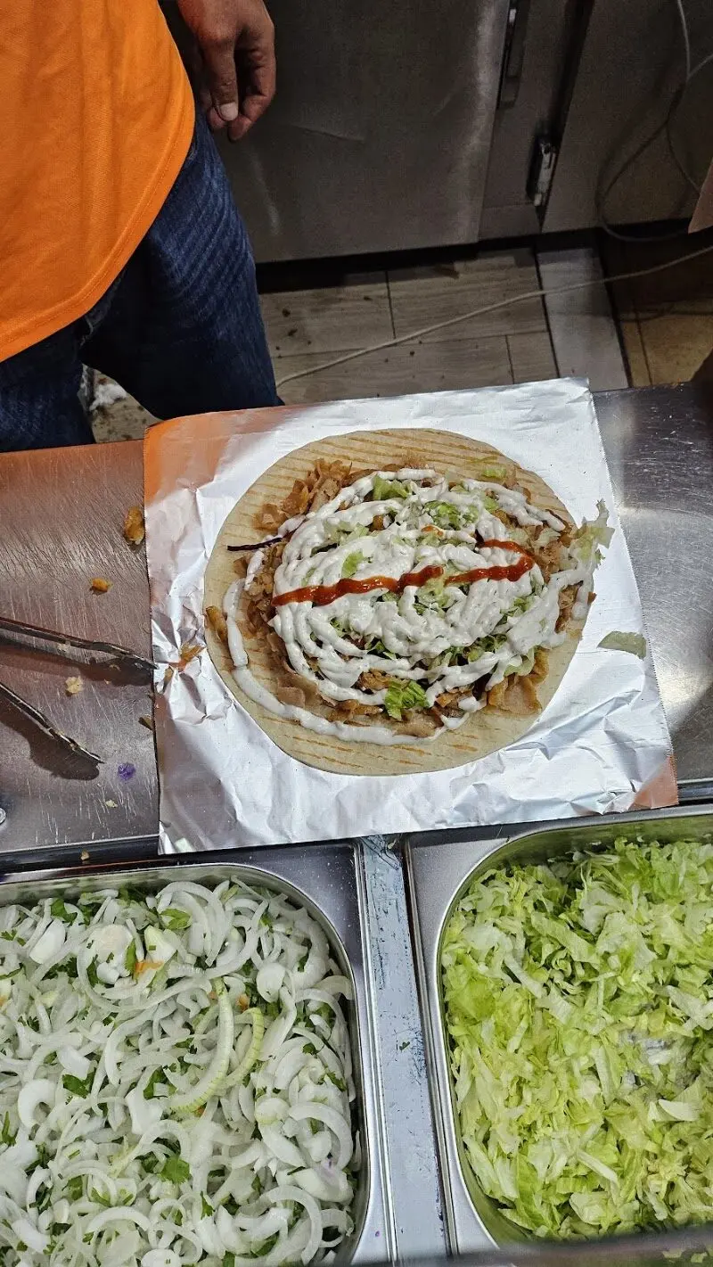 Kebab en pan plano con carne, lechuga, salsa blanca y salsa picante antes de enrollar