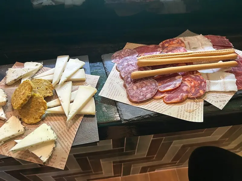 Tablas de quesos curados y embutidos ibéricos con picos de pan sobre papel de periódico