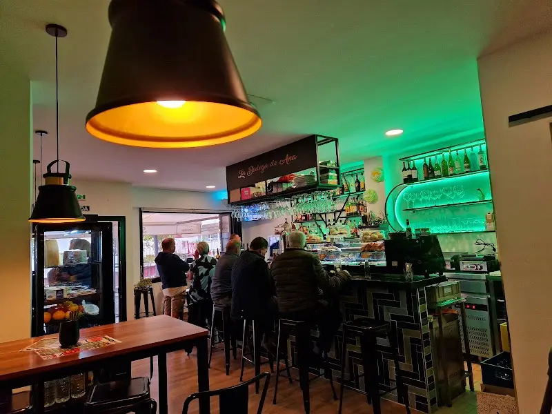 Interior con barra alicatada, estanterías iluminadas en verde y clientes en taburetes