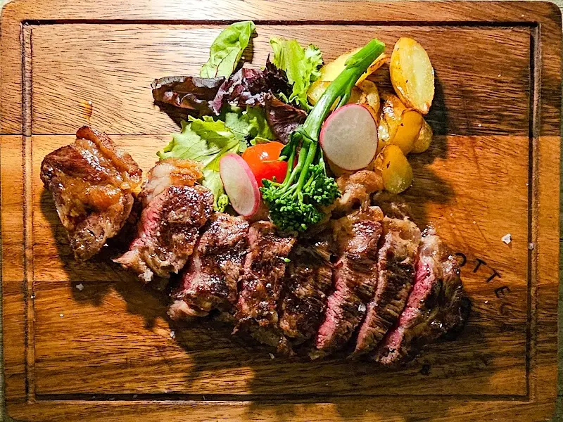 Carne a la brasa en tabla de madera con patatas, brócoli, rabanitos y ensalada