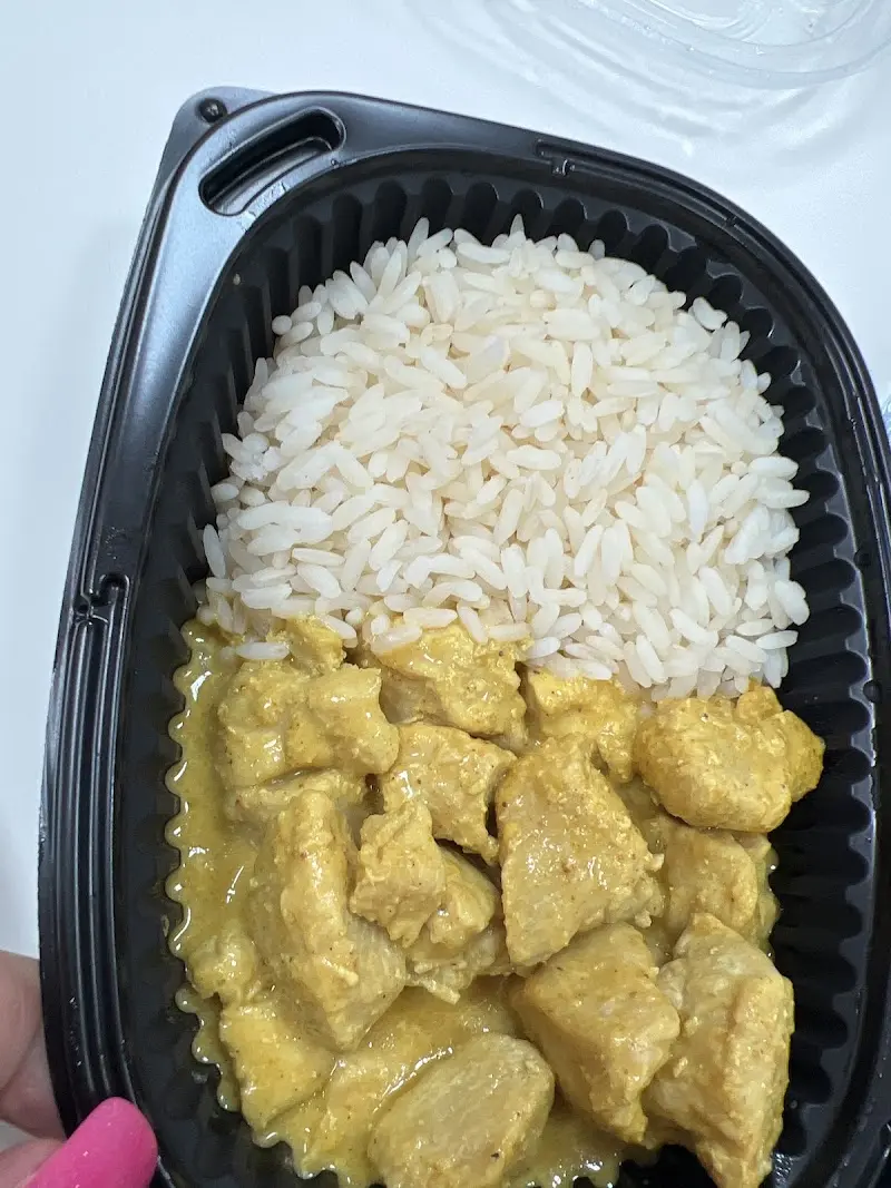 Tarrina para llevar con pollo en salsa de curry y arroz blanco