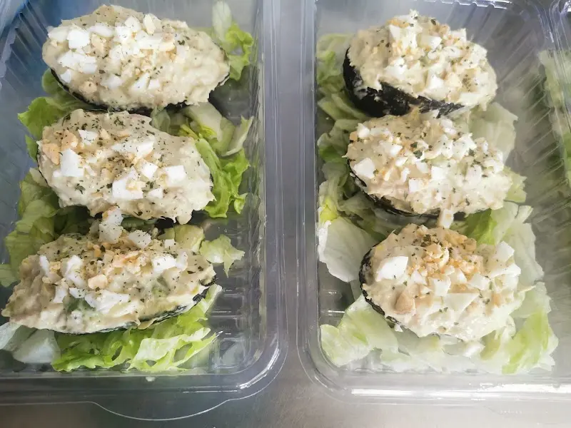 Piezas rellenas de ensalada con huevo picado sobre lechuga en envases para llevar