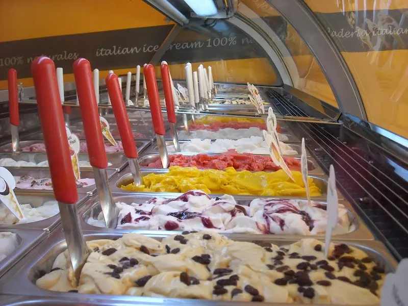 Cubetas de helado con espátulas rojas, entre ellos sabores de fruta y nata con pasas