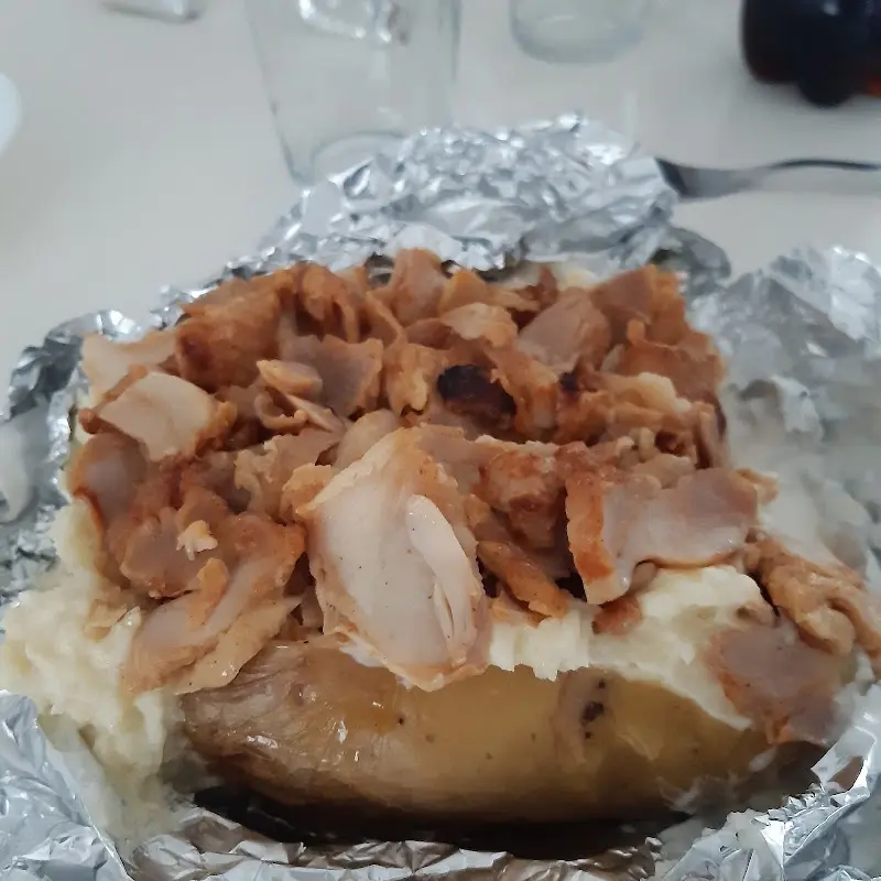 Patata asada con carne de kebab sobre puré, servida en papel de aluminio