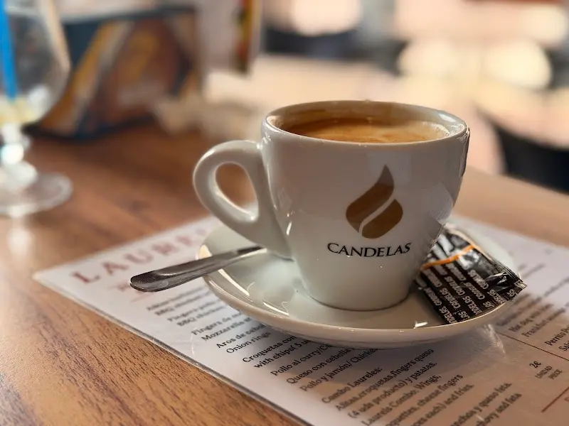 Taza de café solo sobre la carta, con cucharilla y chocolatina en el platito