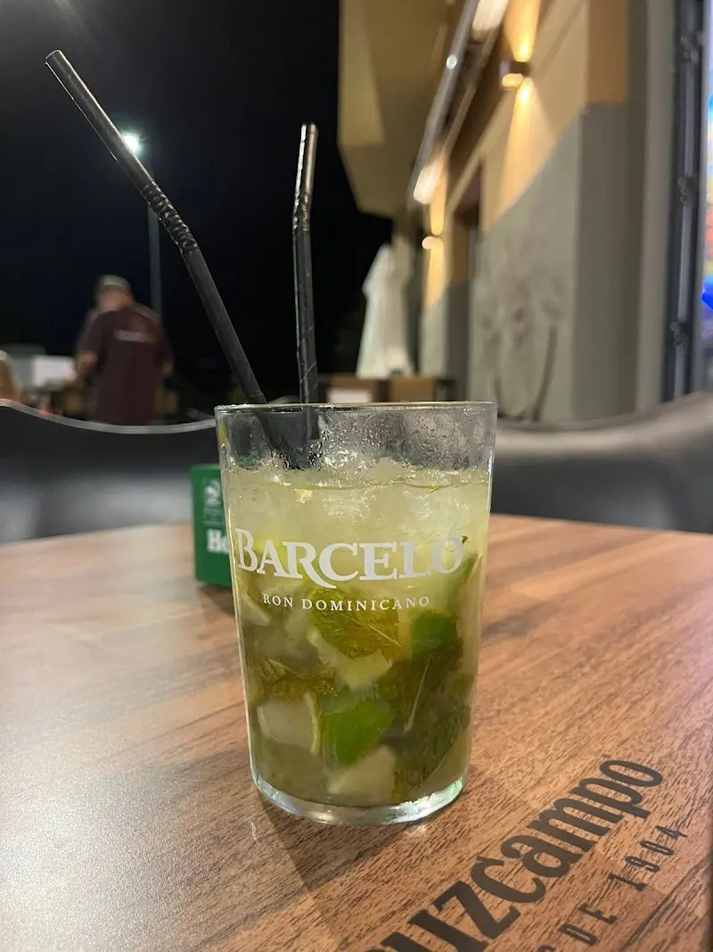 Mojito con hierbabuena y hielo picado en vaso con pajitas, en la terraza de noche