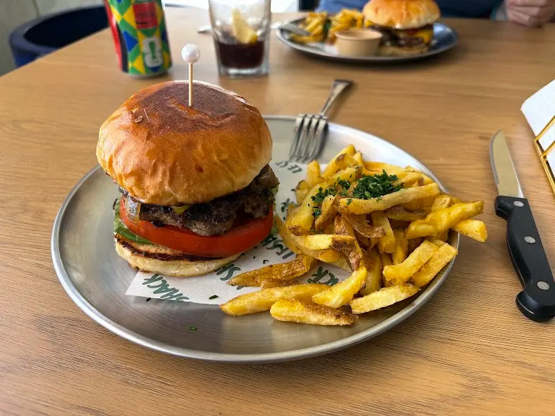 Hamburguesa con tomate y lechuga en pan brioche, con patatas fritas y cebollino