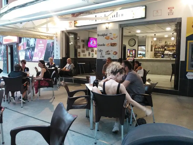 Terraza de la cafetería Leyland al anochecer, con clientes en las mesas y la barra al fondo
