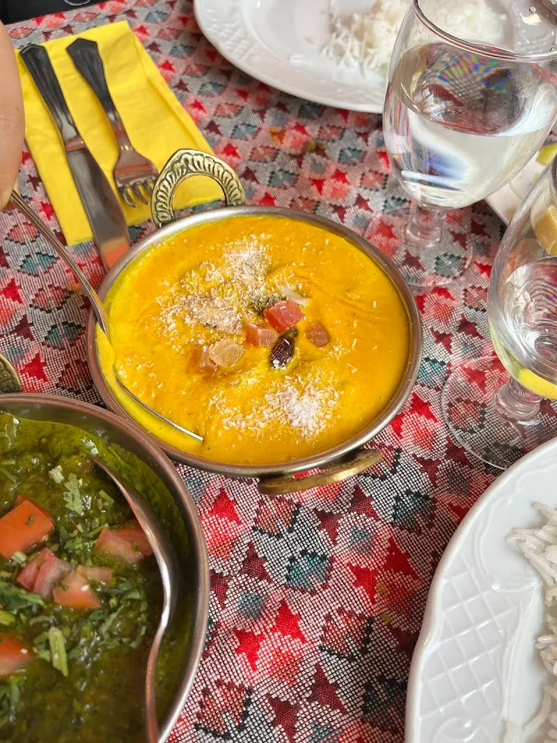 Curry amarillo cremoso con coco rallado y frutos secos en un cuenco metálico