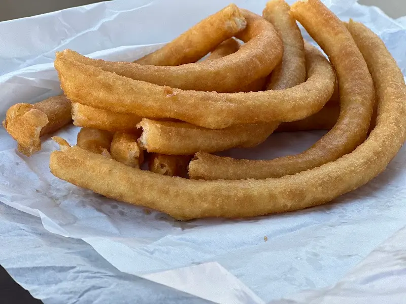 Ración de churros recién hechos sobre papel blanco