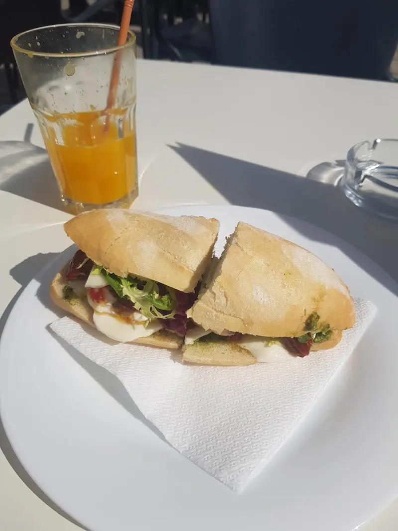 Bocadillo de mozzarella, pesto y lechuga con un zumo de naranja en la terraza al sol